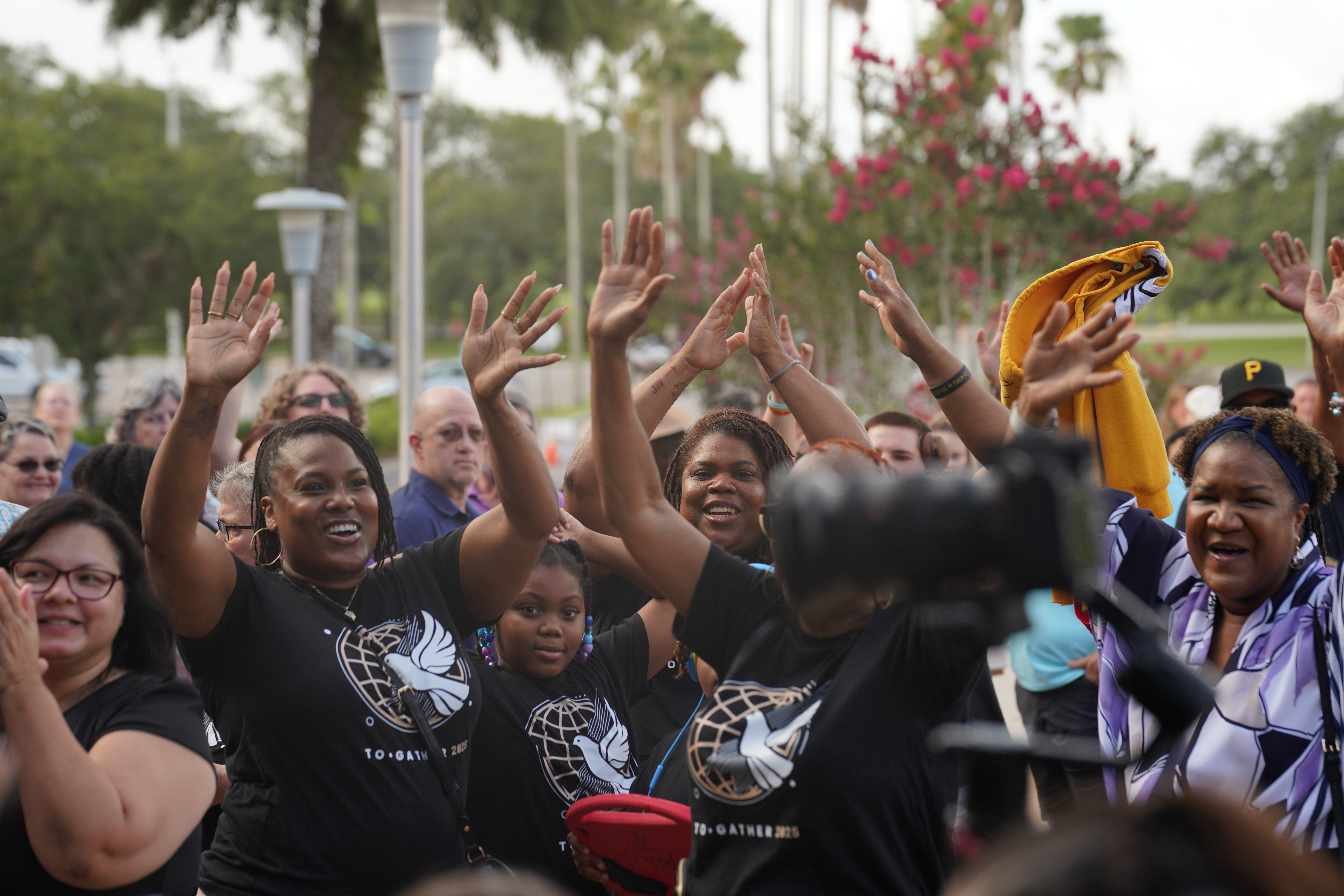 Crowd with hands raised outdoors at To·Gather